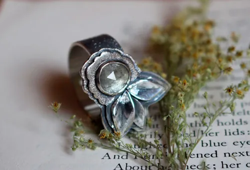 Fleurir sous l’univers, bague fleur et pétales en argent et saphir transparent